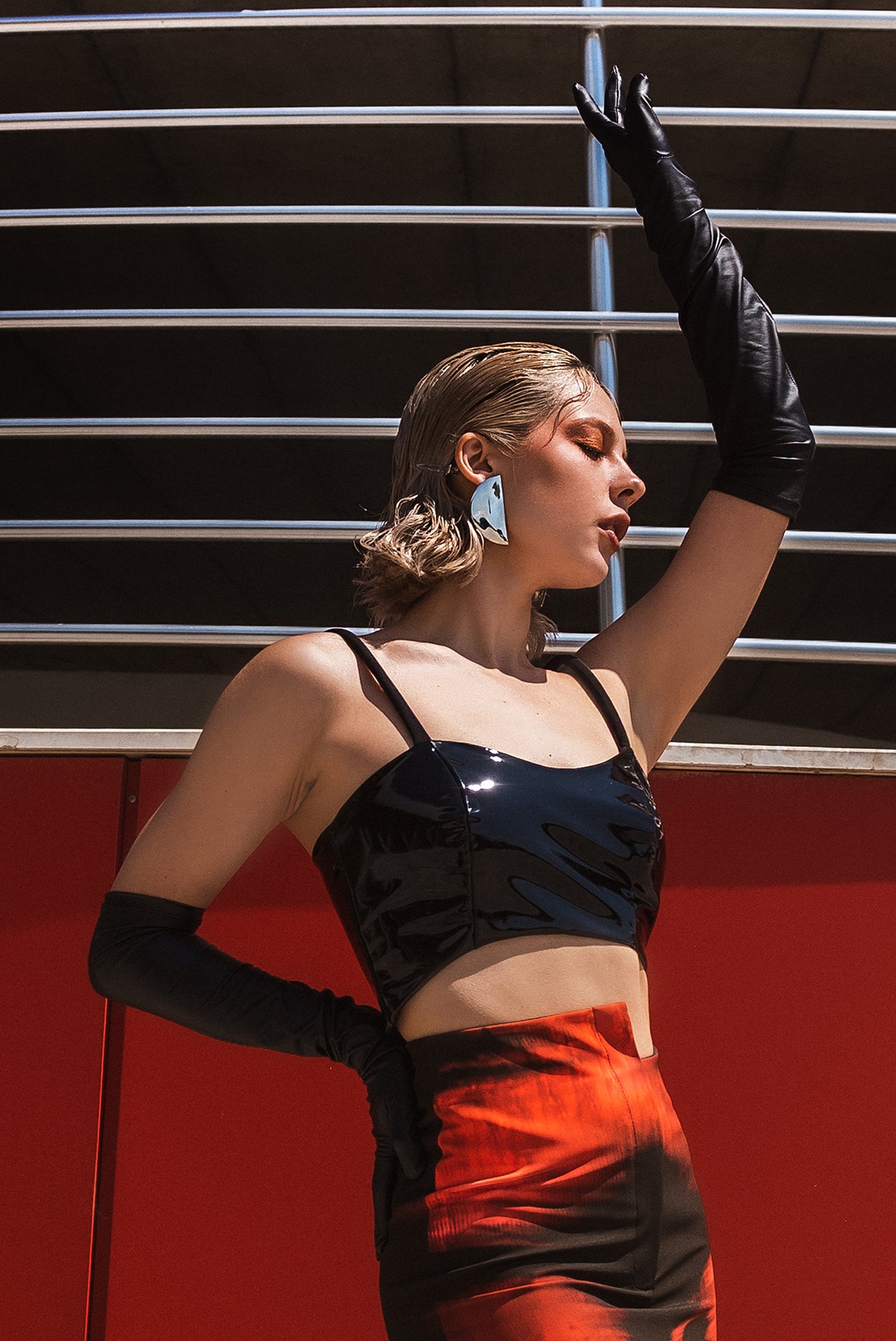 The model wears a black asymmetric crop top with rope straps. It is made from 100% eco leather, closed with soft lining. The outfit also contains our long stepped skirt. One remarkable look which will make you stand out.