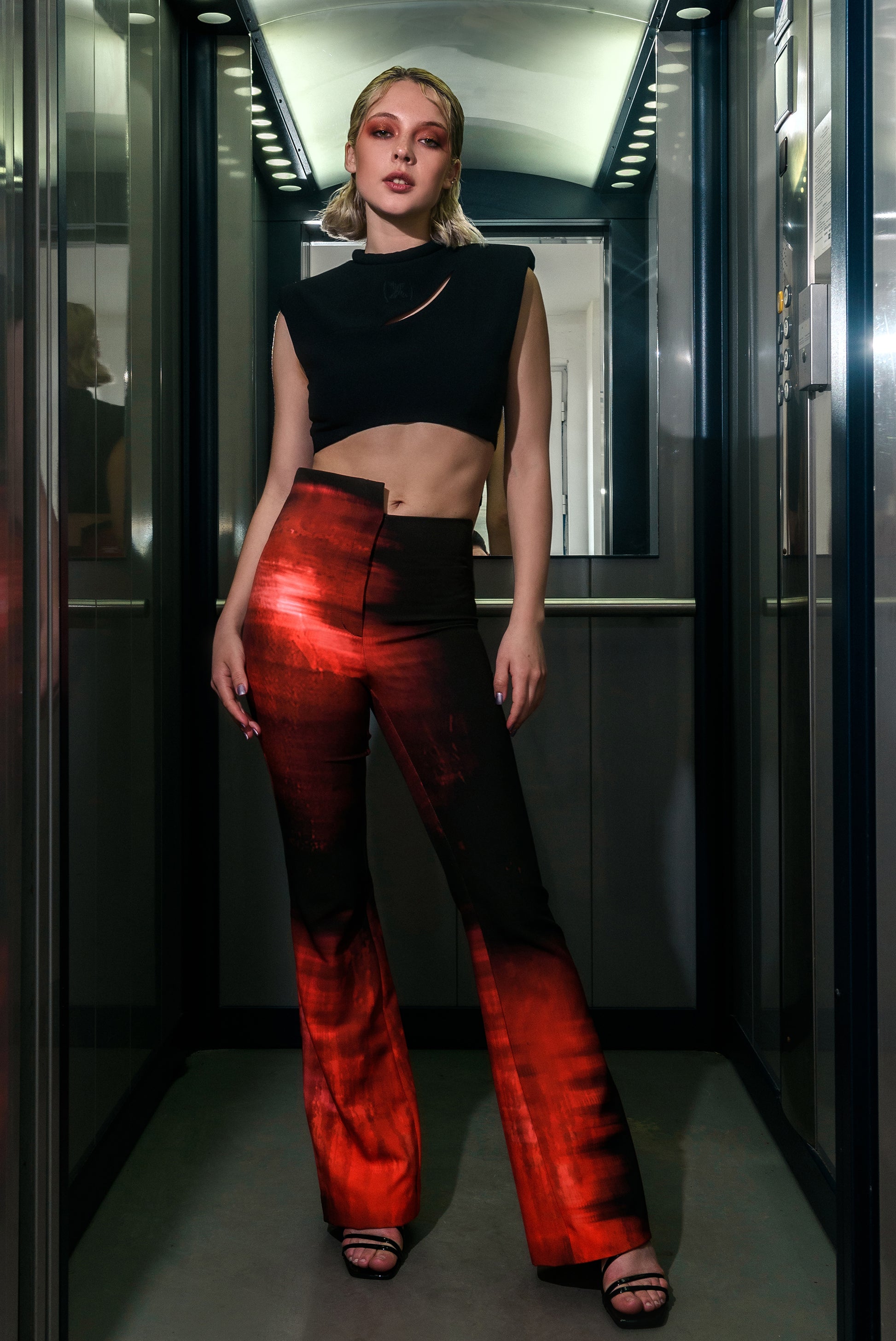 The model wears our cut-out pants with stepping on the waist and print. The outfit also contains our padded crop top with a neck rope and original embroidery. The products create a modern look for a walk around the city or a night out.